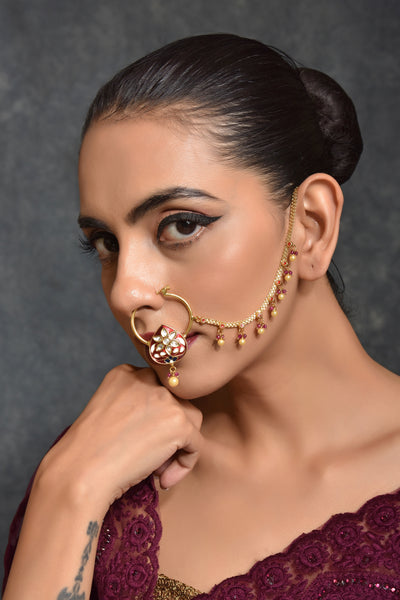 This gorgeous nose ring has red enamel paint to suit the wedding outfit. Also, the studded Kundan stones make it distinct and classy. The pearl drops along the chain add to the beauty.